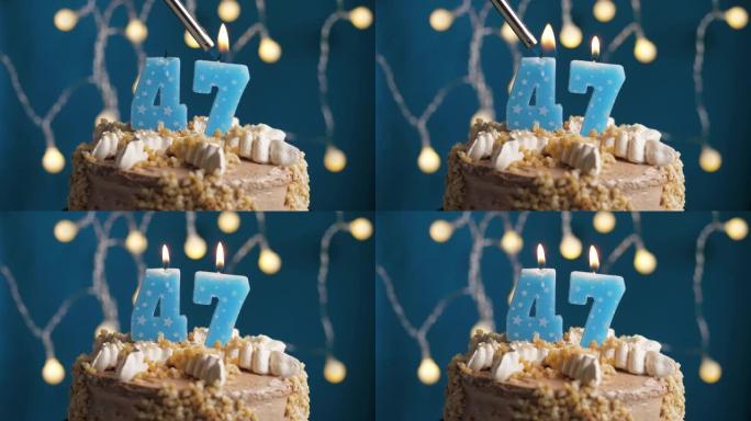 蓝色背景上有47号蜡烛的生日蛋糕。蜡烛着火了。慢动作和特写视图