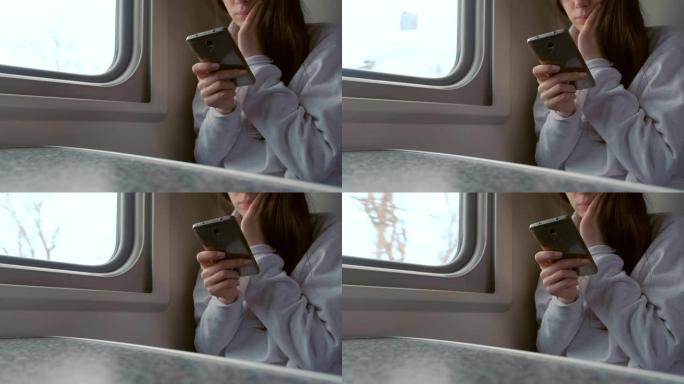 疲惫的年轻女子在火车上看手机视频。双手特写。