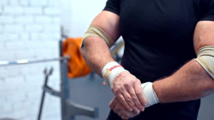 运动员纠正手腕和手部肌肉上的弹性绷带。在健身房训练的准备。特写。