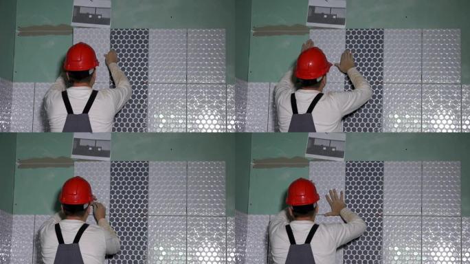 戴着防护头盔的熟练工人在墙上铺设瓷砖