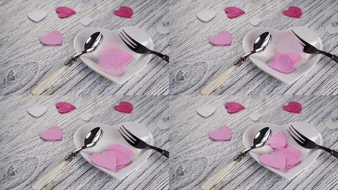 装饰心落在带有甜点叉和勺子的心形盘子上。在木制轻纹理桌上