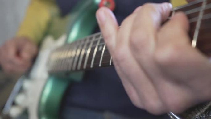吉他大师的手在脖子上滑动的特写镜头，在金属绿色老式电吉他上弹奏和弦，音阶和独奏