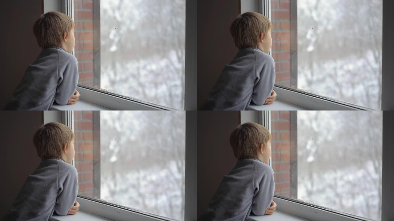 一个小男孩透过窗户看着大雪，等待圣诞节的到来。慢动作镜头