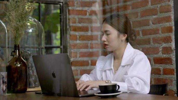 亚洲妇女在咖啡馆使用笔记本电脑