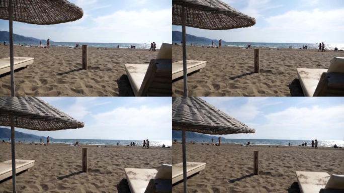 夏日，海景和沙滩的美丽景色，配有稻草太阳伞。豪华度假村配有躺椅的舒适场所。海洋海岸附近平静的田园风光