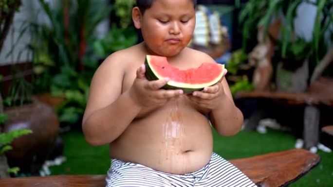 快乐的亚洲男孩在户外吃西瓜