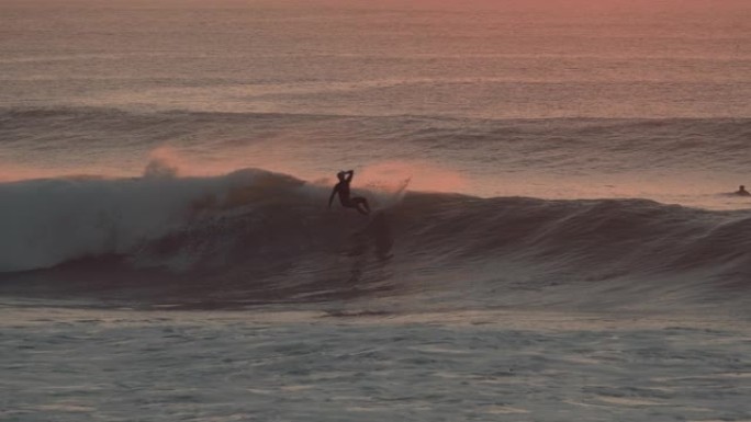 一位专业冲浪者在日落/日出时冲浪完美波浪的美丽照片。