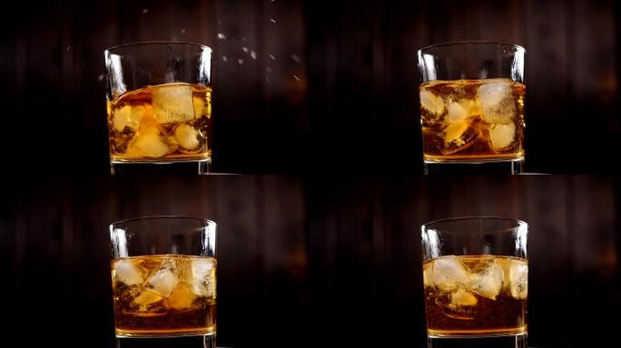 在木制背景上，冰块落入一杯威士忌中的特写镜头。