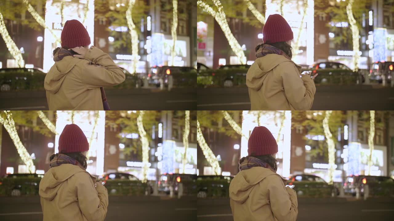 亚洲女孩戴上羊毛帽子和围巾在晚上在城市等待出租车。