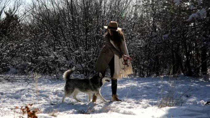 冬天，带着哈士奇狗的女人在森林里玩得开心