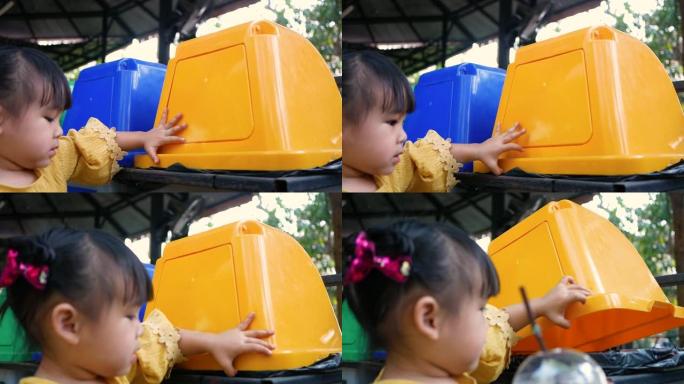 可爱的小女孩在户外咖啡馆的回收箱里扔塑料饮料杯。拯救世界的概念。零浪费。