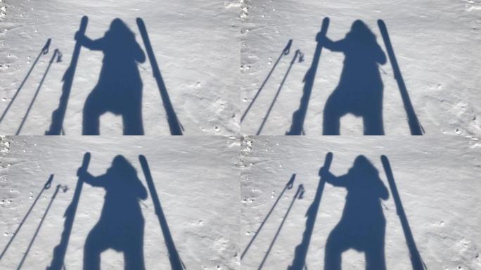女滑雪者影子站在雕刻滑雪板和滑雪杖之间的雪地上