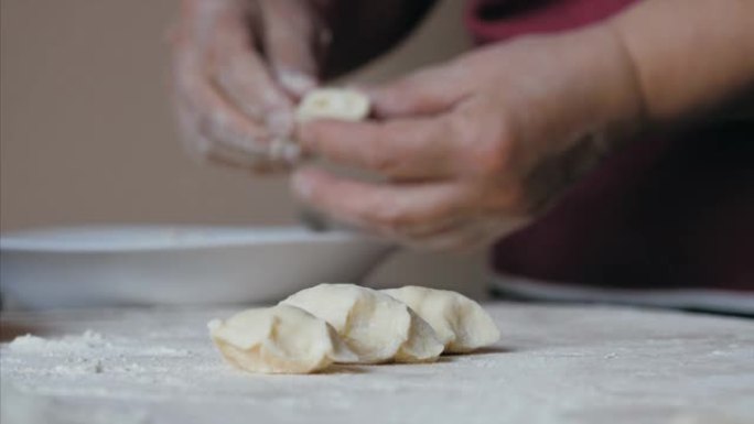 成熟的女性手在家庭厨房用奶酪包饺子