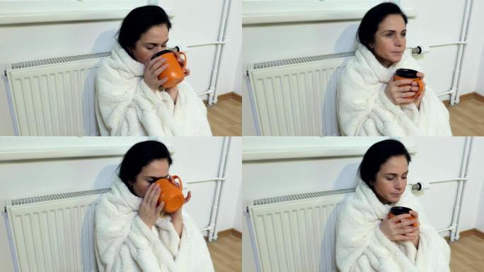 穿格子衣服的女人坐在散热器前喝茶