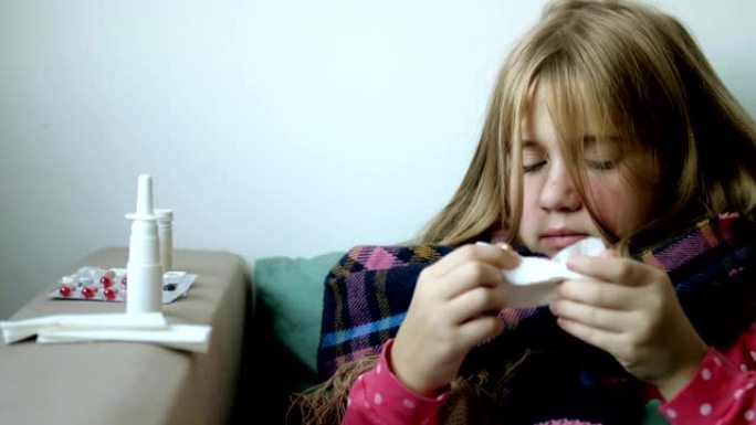 穿着温暖围巾的小女孩吹鼻子。患有鼻炎和咳嗽的生病的孩子