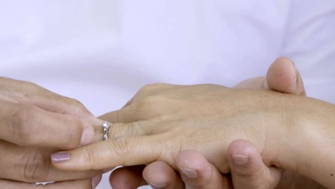特写男人的手把结婚戒指戴在女人的无名指上。