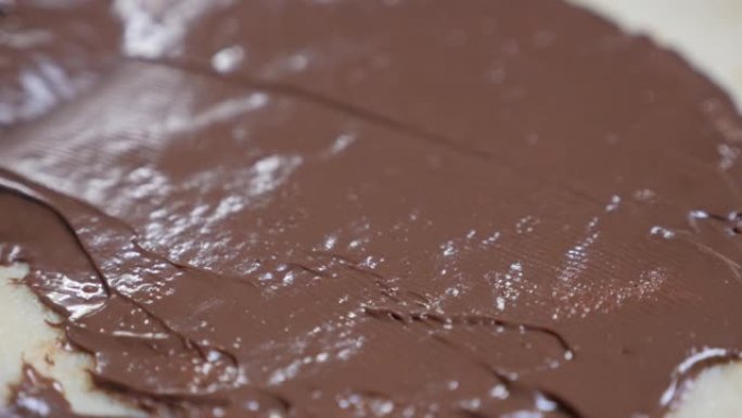巧克力浇头的慢动作特写镜头准备在美味的甜点上滚动