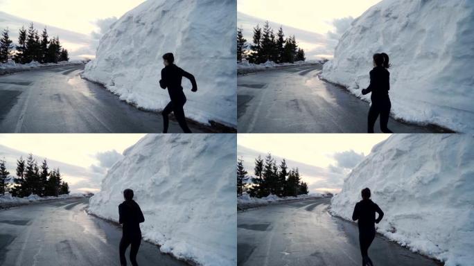 穿着粉红色鞋子的运动女人在沥青路面上奔跑，侧面堆满了大堆雪