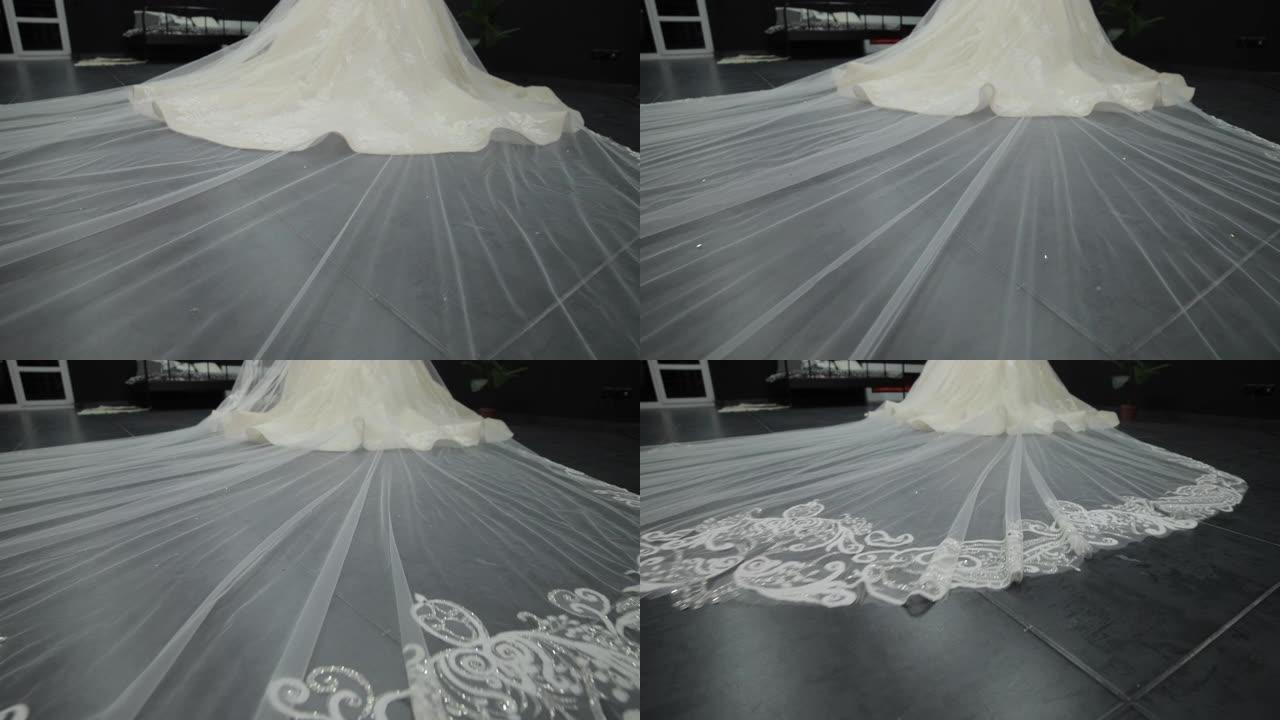 白色婚纱上的长薄纱的特写镜头，横跨地板