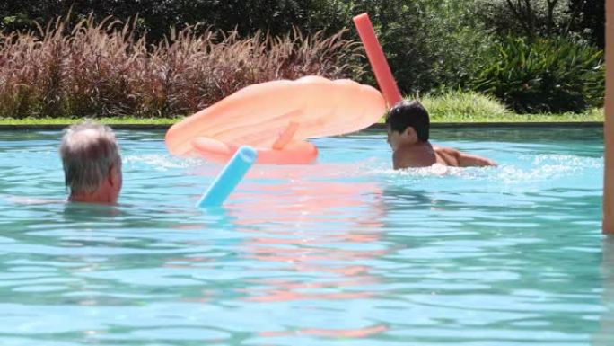 儿童男孩在游泳池玩充气床垫掉进水里