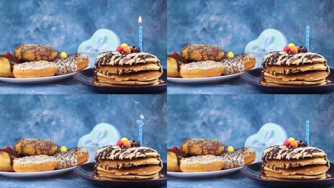 在桌子上的美味煎饼上吹蓝色蜡烛，并带有礼物和甜甜圈，用于生日聚会