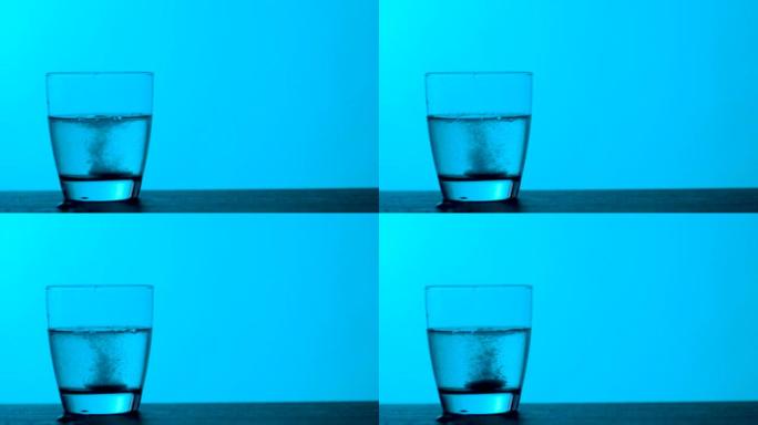 泡腾片滴入一杯水蓝色背景，慢动作
