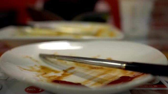 在餐厅吃完食物后空盘子。用筷子。背景模糊是一个小女孩在吃饭。