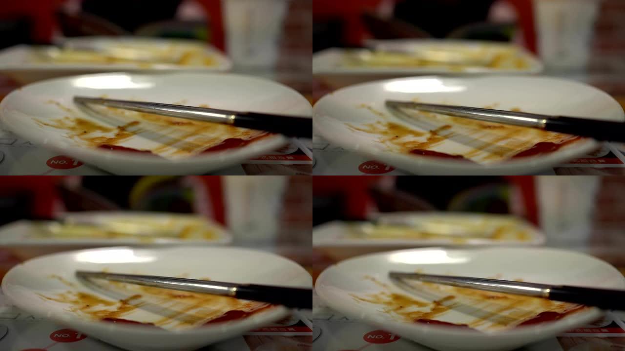在餐厅吃完食物后空盘子。用筷子。背景模糊是一个小女孩在吃饭。