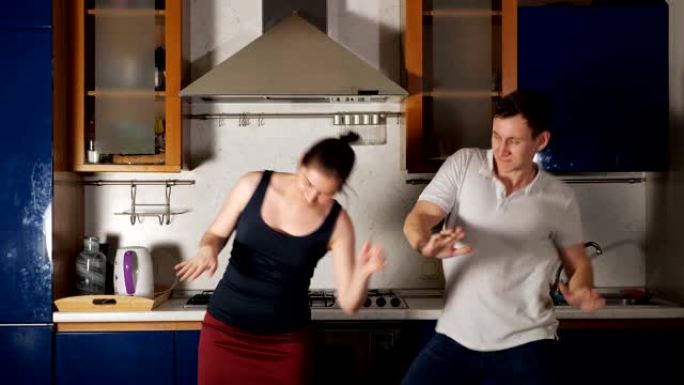 快乐的男人和女人跳舞，跳起来在厨房玩得开心