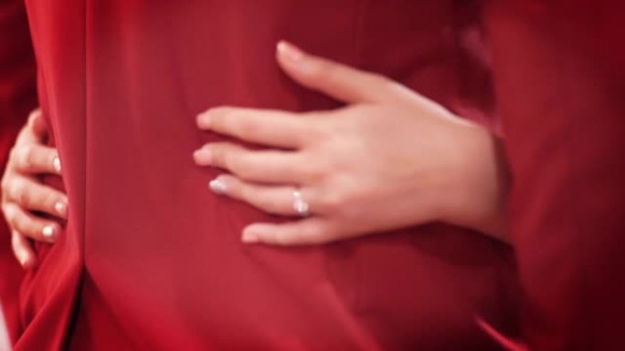新娘站在一起时，穿着红色西装轻轻地拥抱新郎