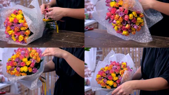 女花店在花店用纸包装玫瑰花束，双手特写。