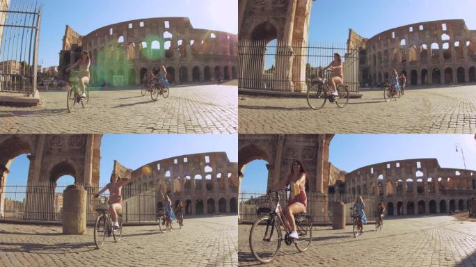 三个快乐的年轻女性朋友日出时在意大利罗马罗马斗兽场骑自行车的游客。