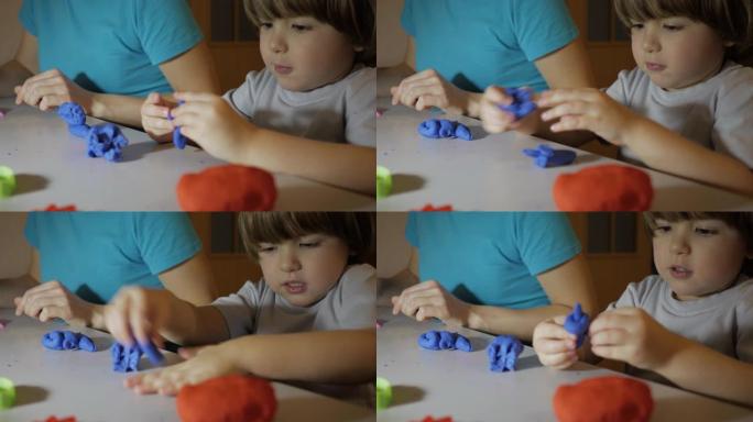 儿童在托儿所的餐桌上对橡皮泥进行建模。儿童男孩和母亲在家里的游戏室玩彩色粘土玩具。年轻的女人和儿子在