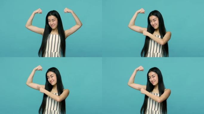 我坚强独立。亚洲女子长发举起手臂显示二头肌，指向苗条手上的肌肉