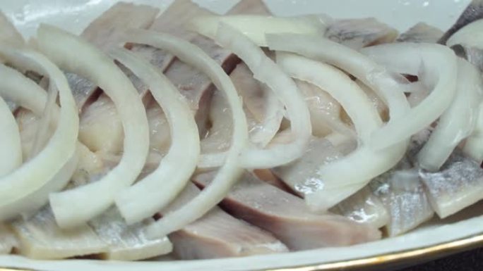 洋葱的鲱鱼片放在盘子里的油里。绕着圈旋转。