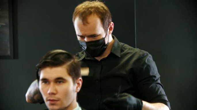 理发师在颈背镜反射上刷年轻男子客户的湿头发