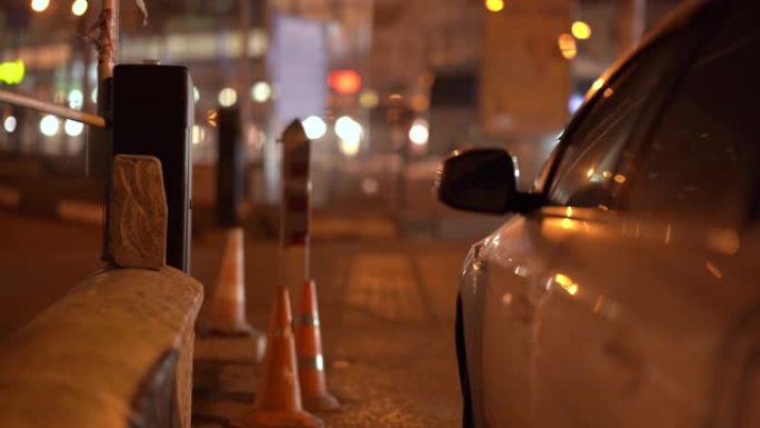 夜间城市街道上的汽车，自动道路屏障门，模糊的城市交通信号灯。