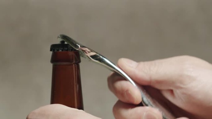 用手打开一瓶带有开瓶器的深色工艺烈性啤酒
