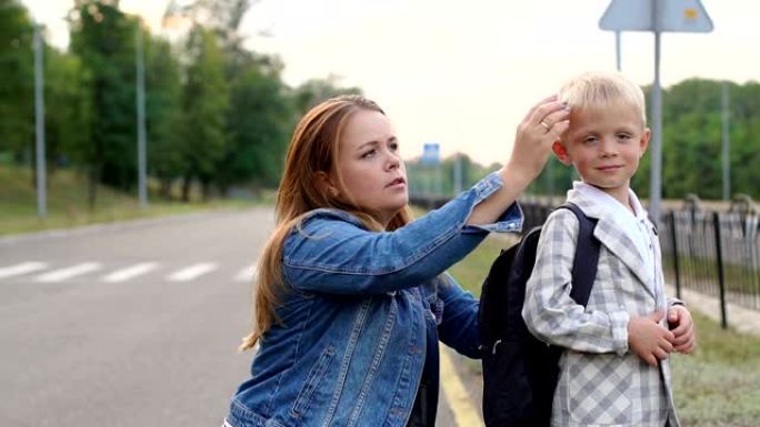 一位有爱心的母亲的特写镜头在上学前调整了他背上的背包。
