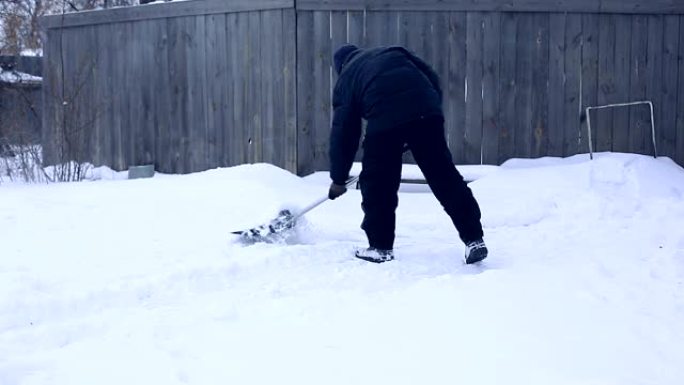 雪夜后工作。在一个寒冷的下雪的早晨，男人用铲子从院子里除雪
