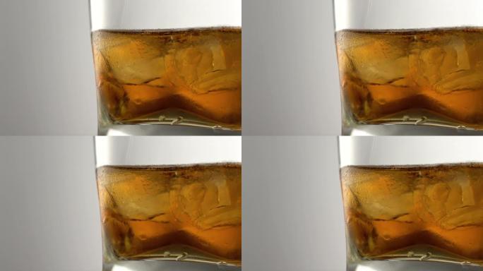 一杯陈年的金威士忌和冰块放在桌子上。酒吧里有石头的琥珀色酒精饮料