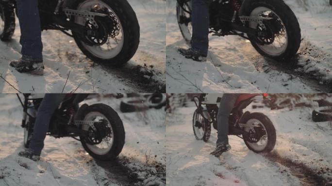 摩托车手在雪地里做轮胎倦怠，慢动作。专业摩托车手在日落时在雪地上漂移并打开摩托车。骑自行车的人在摩托