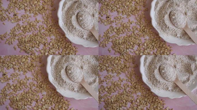 燕麦食品配料 -- 粉色背景上的面粉和薄片