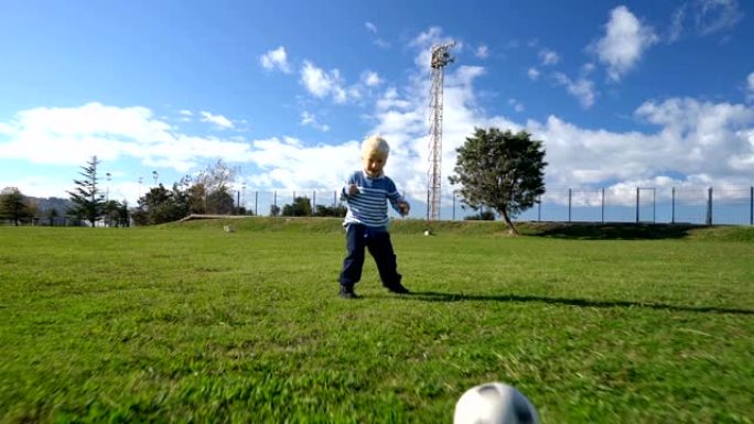 三岁的孩子在足球场上带球奔跑