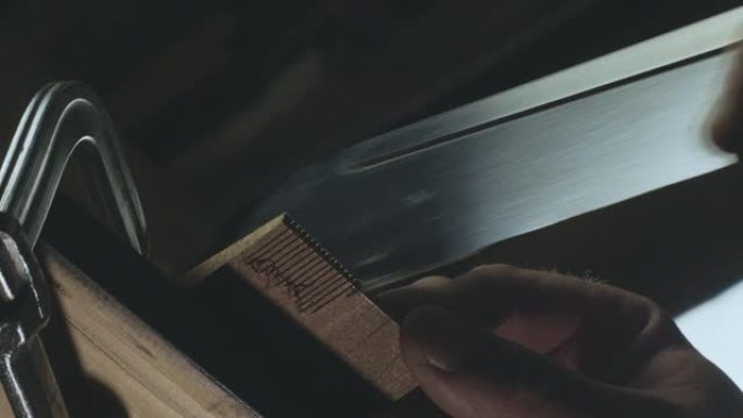 用手锯锯木制细节的人的手的特写。木匠制作手工木梳。电影4k视频