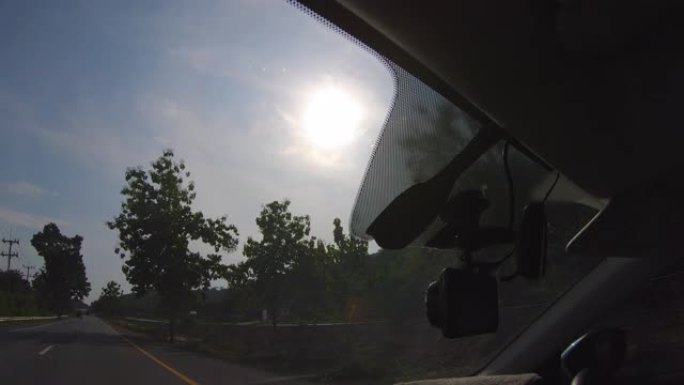 透过汽车前窗看阳光照着道路