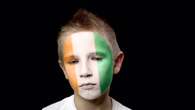 象牙海岸足球队的悲伤球迷。一个脸上涂着民族色彩的孩子。