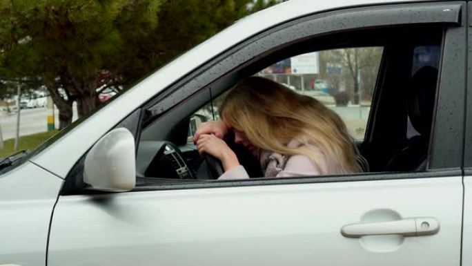年轻的金发女人坐在汽车上，把她的手和头在方向盘上，关闭她的眼睛从乏力，情绪疲惫，压力，缺乏睡眠，问题