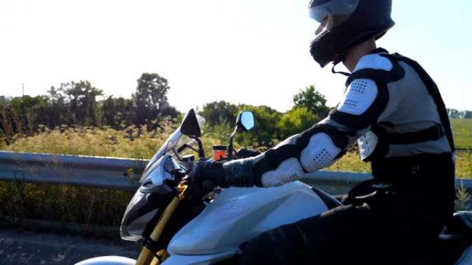 戴着头盔的男子在高速公路上骑着强大的运动摩托车。摩托车手在乡间小路上骑摩托车。骑摩托车的人在旅行中骑