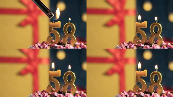 生日蛋糕58号点火器燃烧的金色蜡烛，蓝色背景礼物黄色盒子用红丝带绑起来。特写和慢动作